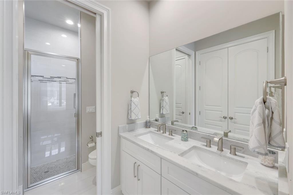 Bathroom with double vanity, a stall shower, and recessed lighting