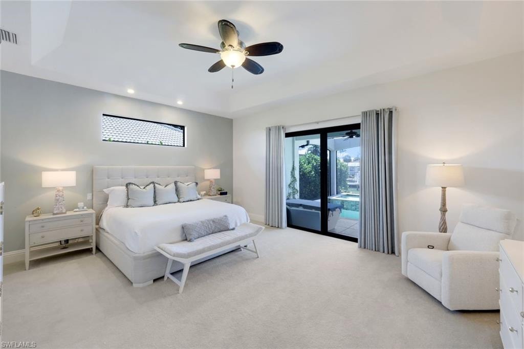 Bedroom with a tray ceiling, access to outside, light colored carpet, a ceiling fan, and recessed lighting