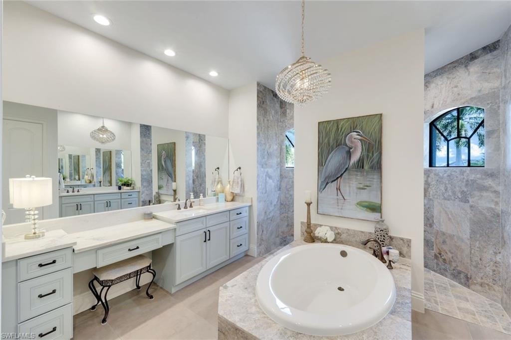 Bathroom featuring a bath, vanity, a chandelier, and a walk in shower