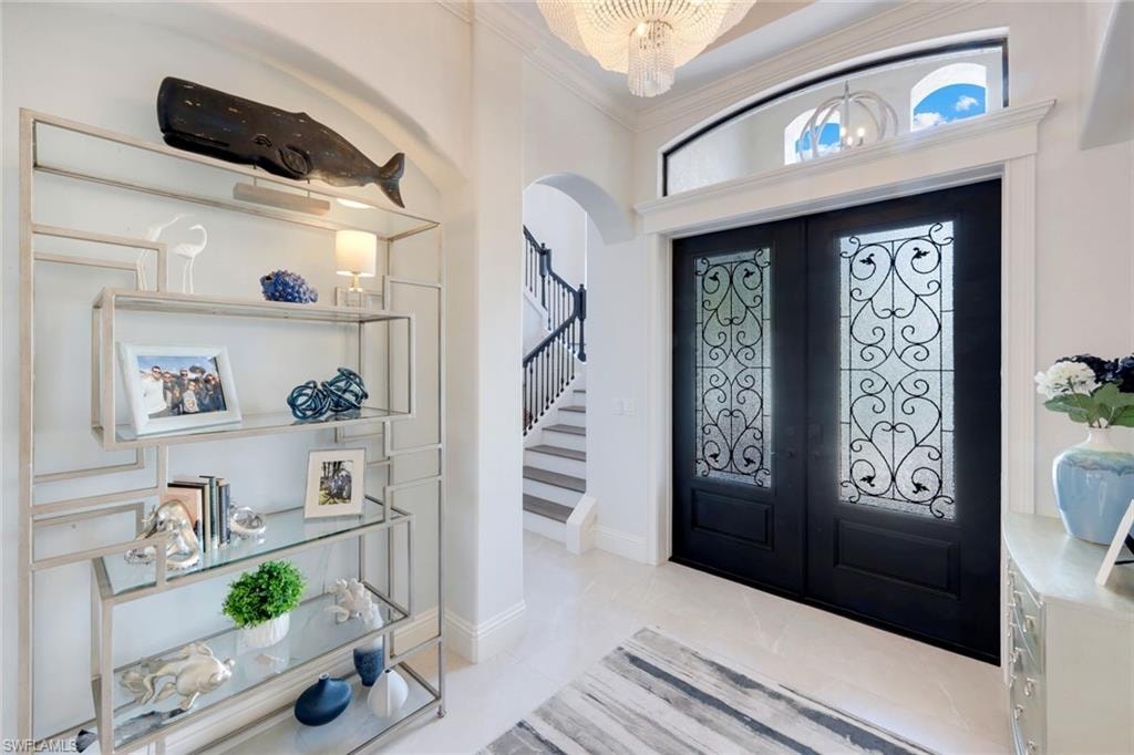 Foyer with french doors, arched walkways, crown molding, and light tile patterned floors