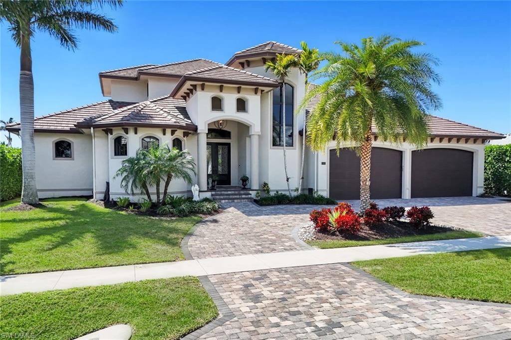 Mediterranean / spanish-style home with decorative driveway, a front yard, stucco siding, a tiled roof, and a garage