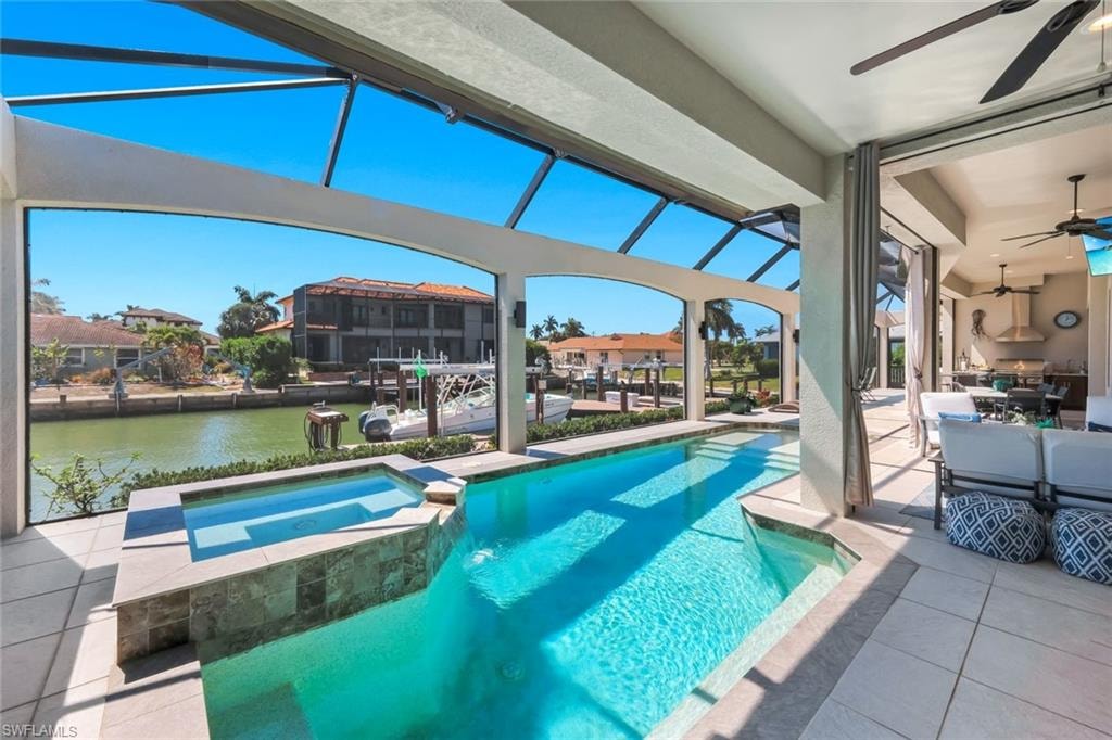 Relaxing pool / spa with a sunroom, a patio, a water view, a lanai, and outdoor dining area