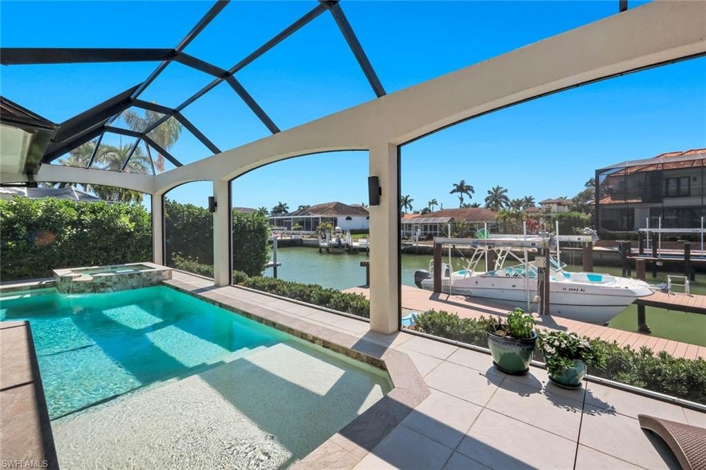 Combined pool / hot tub with a water view, a boat dock, a sunroom, boat lift, and a patio