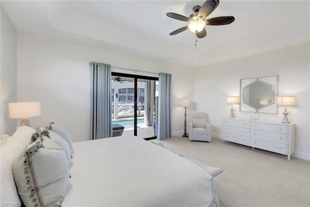 Carpeted bedroom with a tray ceiling, a ceiling fan, and access to exterior