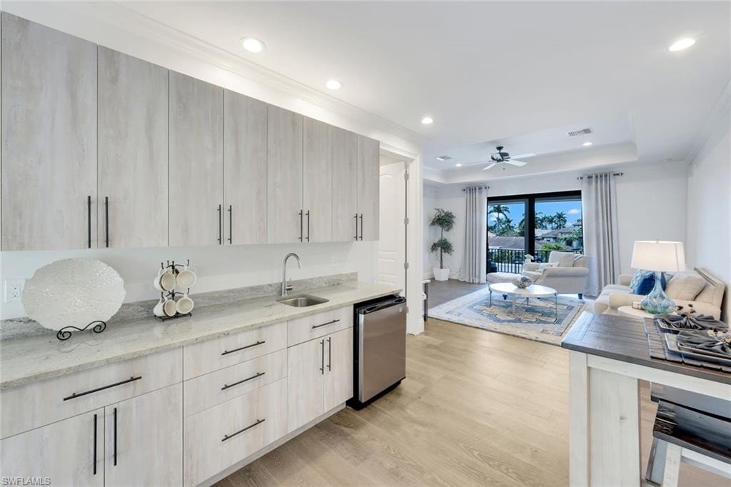 Kitchen featuring light stone counters, open floor plan, light wood finished floors, a ceiling fan, and modern cabinets