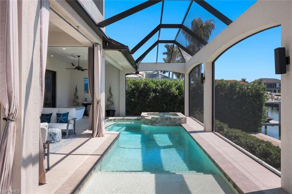 Integrated pool / hot tub featuring a sunroom, a patio, glass enclosure, and a water view