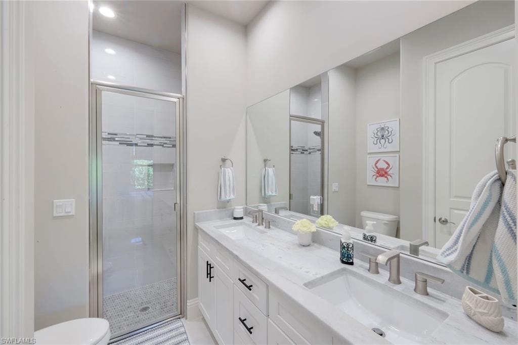Bathroom featuring double vanity, a stall shower, and recessed lighting