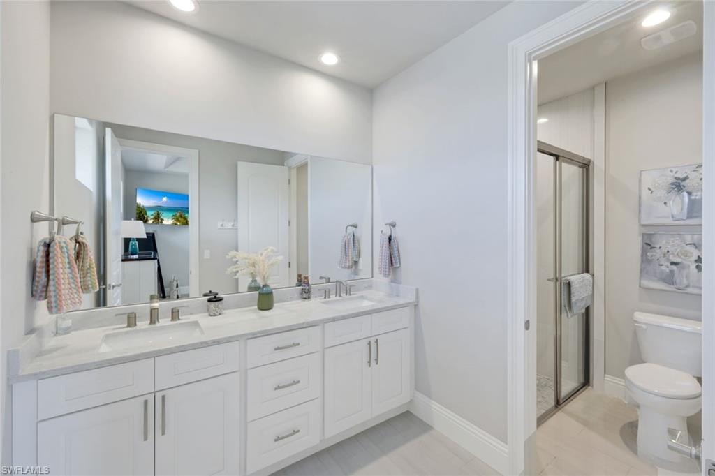 Full bath with double vanity, a shower stall, and recessed lighting
