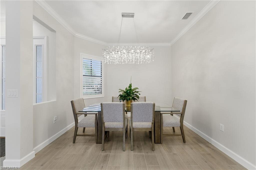 Dining room with wood tiled floors, crown molding, and a chandelier