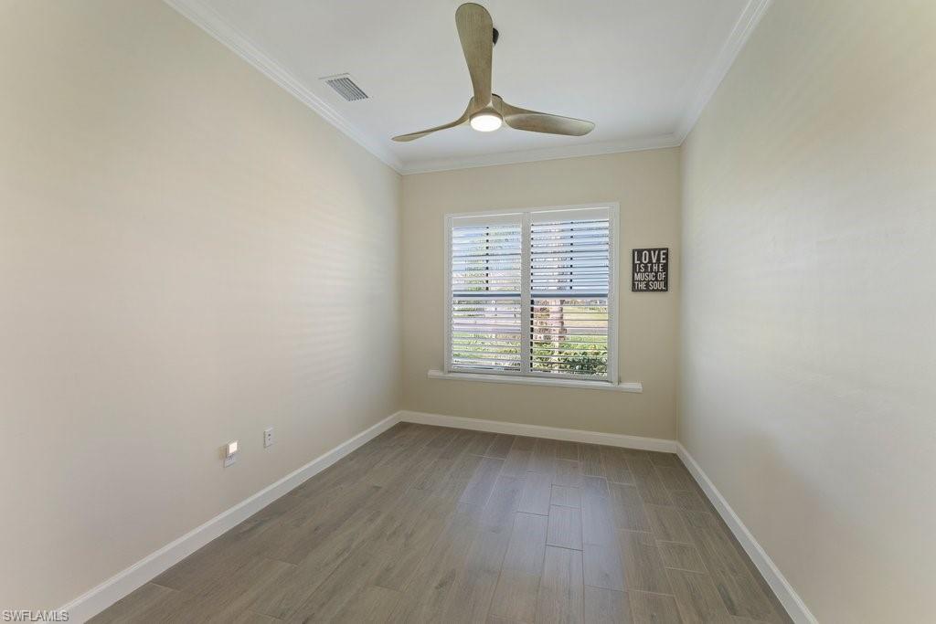 Spare room with wood finished floors, ornamental molding, and a ceiling fan