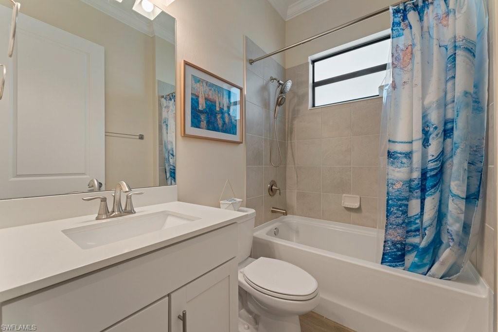 Full bathroom featuring vanity, shower / bath combo with shower curtain, and ornamental molding
