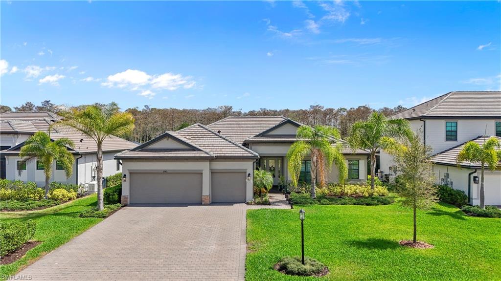 View of front of house featuring a front lawn, a garage, driveway, and a tile roof