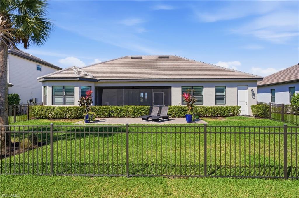 Rear view of house with a fenced backyard, a tile roof, and stucco siding