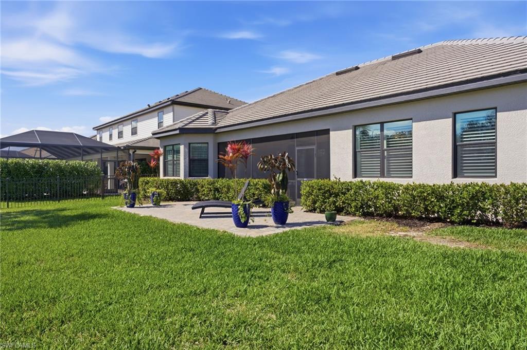 Back of house with a sunroom, a tile roof, a patio area, and stucco siding