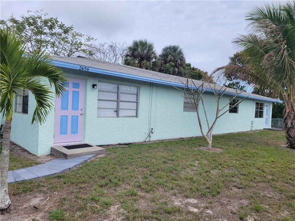 Back of property featuring a lawn and stucco siding