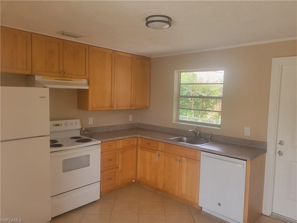 Kitchen featuring white appliances, light tile patterned flooring, and ornamental molding