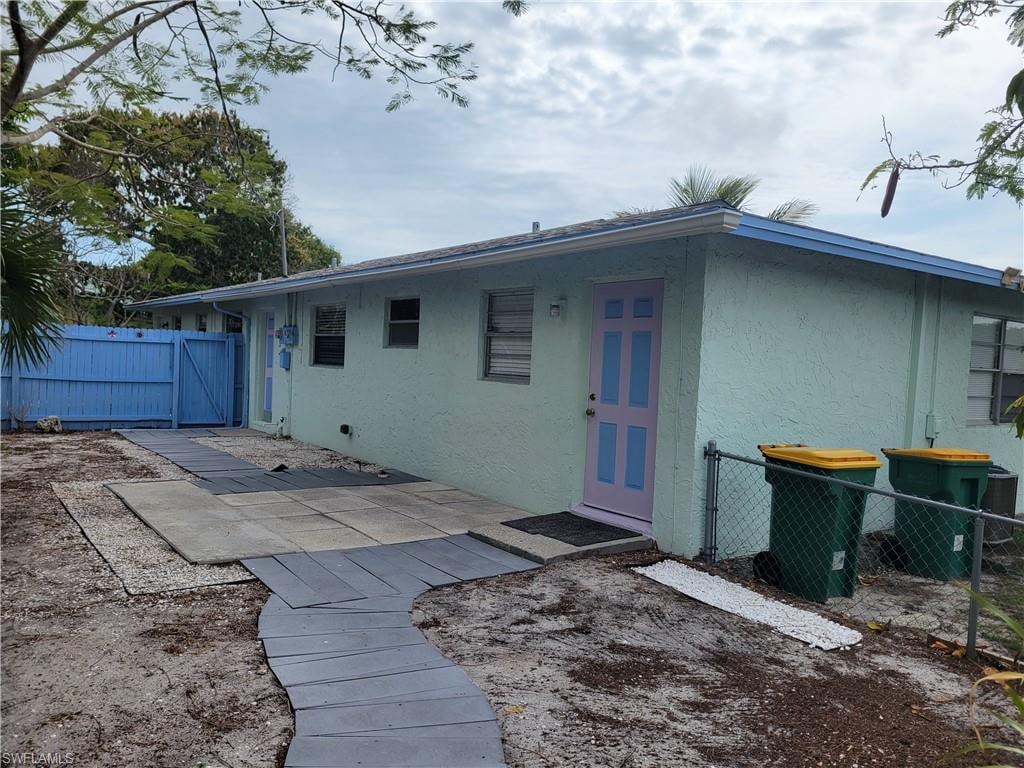 View of front of home featuring a gate, a patio area, and stucco siding