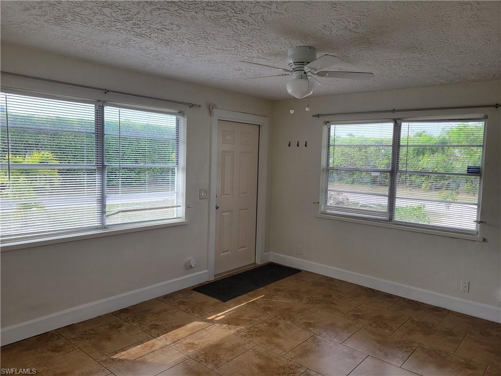 Empty room with ceiling fan and a textured ceiling