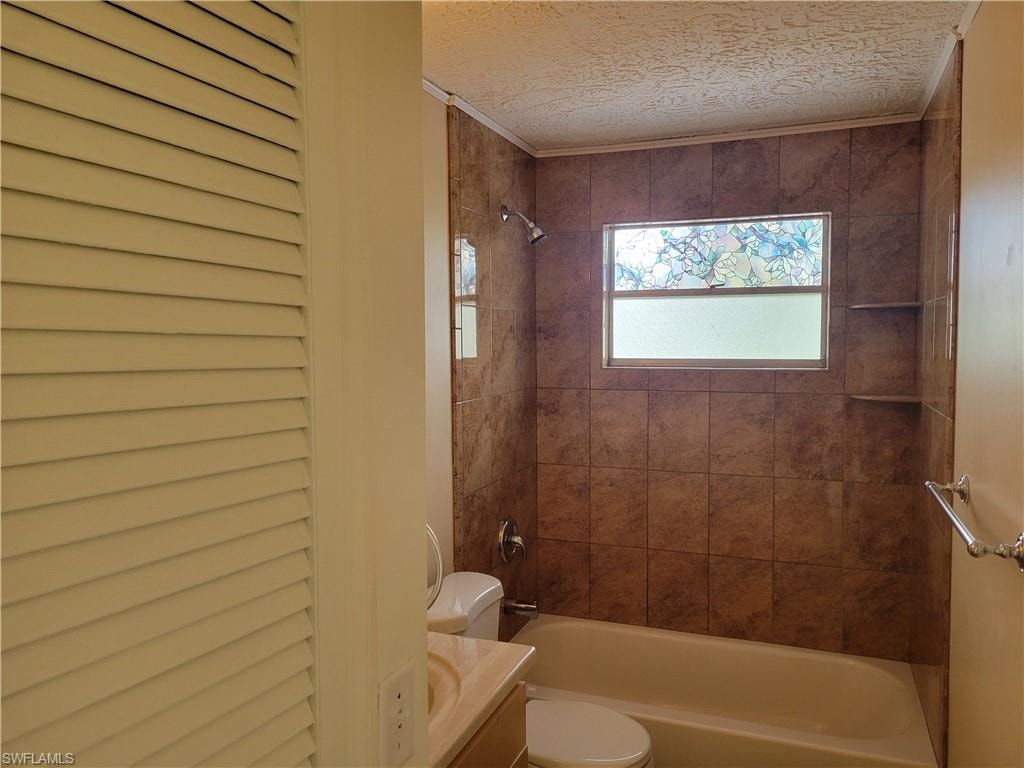 Full bathroom with vanity, shower / bathtub combination, a textured ceiling, and a closet