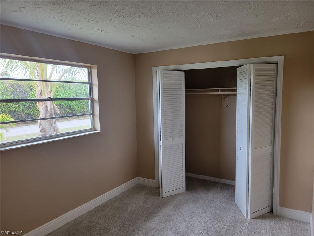 Unfurnished bedroom featuring light colored carpet, a closet, and a textured ceiling