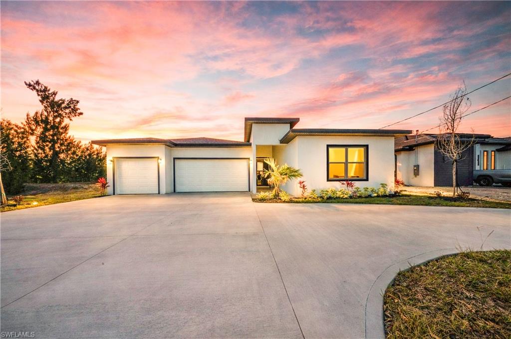 Prairie-style house with driveway, an attached garage, and stucco siding