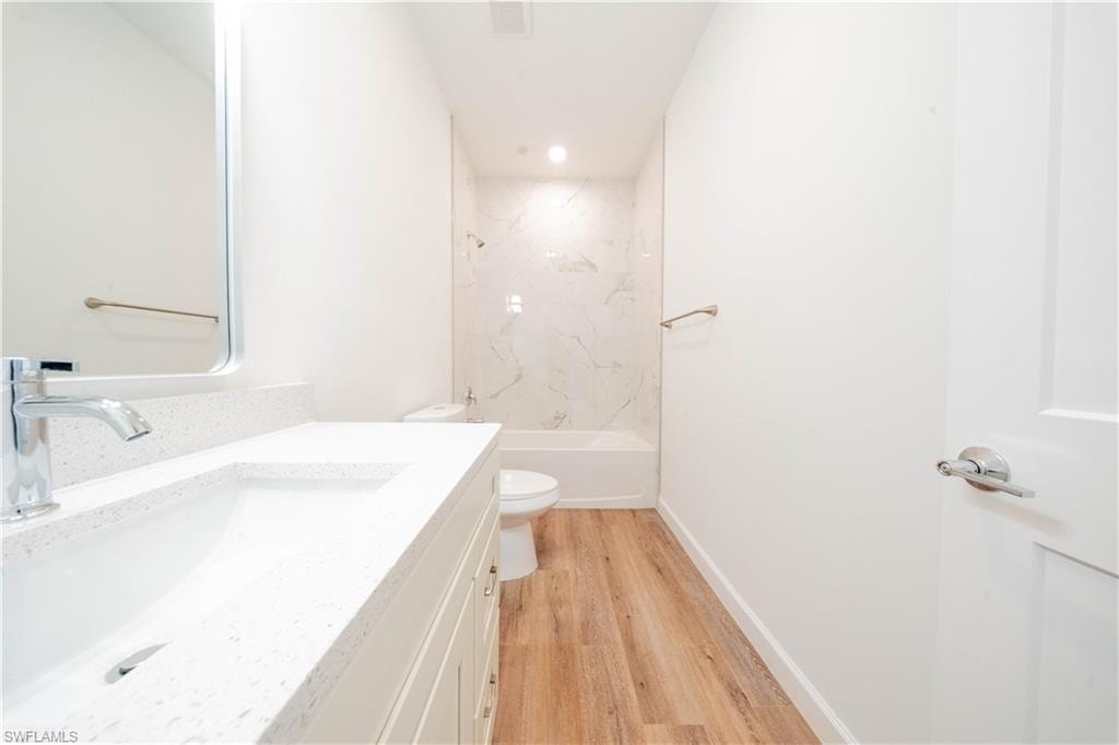 Bathroom with vanity, light wood-style flooring,  shower combination, and recessed lighting