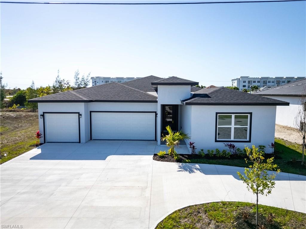 Prairie-style home featuring driveway, an attached garage, stucco siding, and roof with shingles