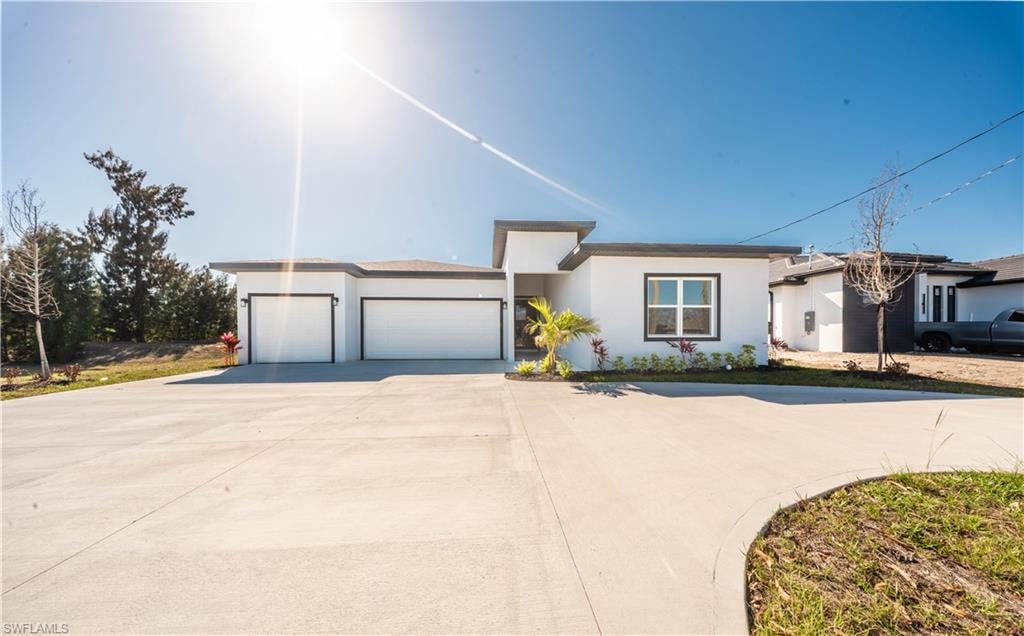 View of front of property with a garage, driveway, and stucco siding