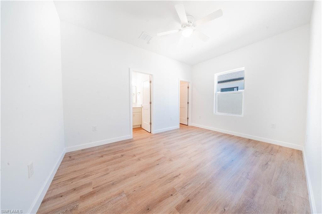 Unfurnished bedroom featuring light wood-type flooring, ensuite bathroom, and ceiling fan