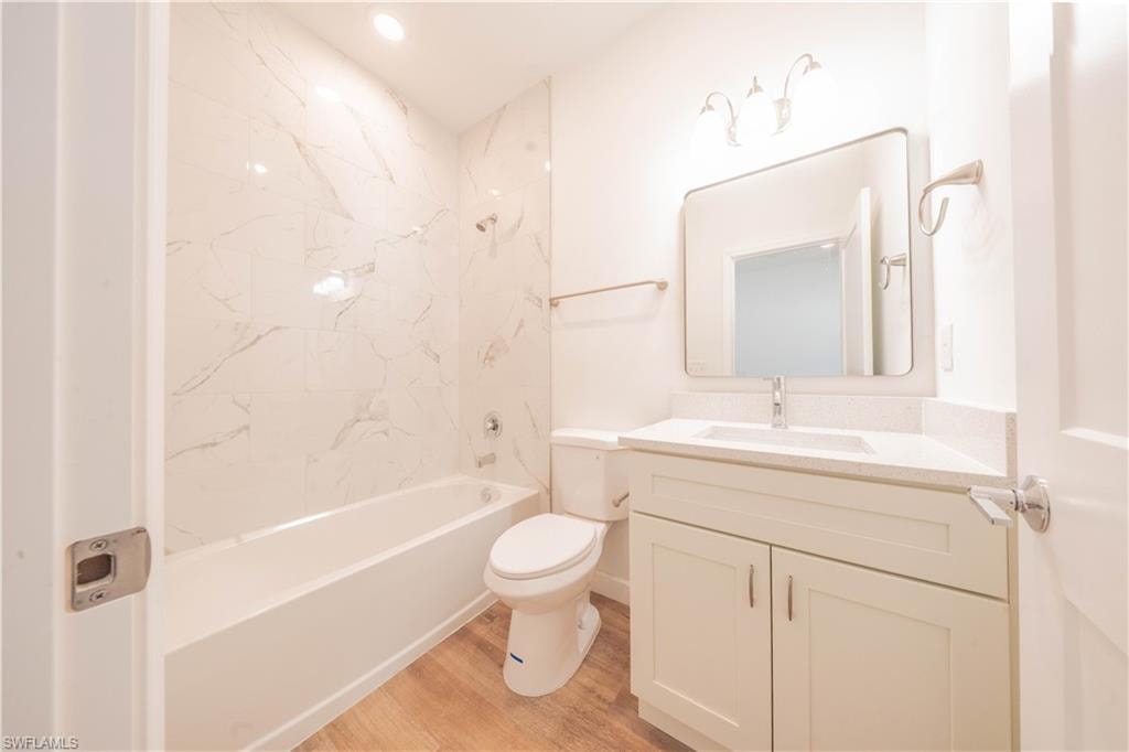 Bathroom featuring vanity,  shower combination, light wood-style floors, and recessed lighting