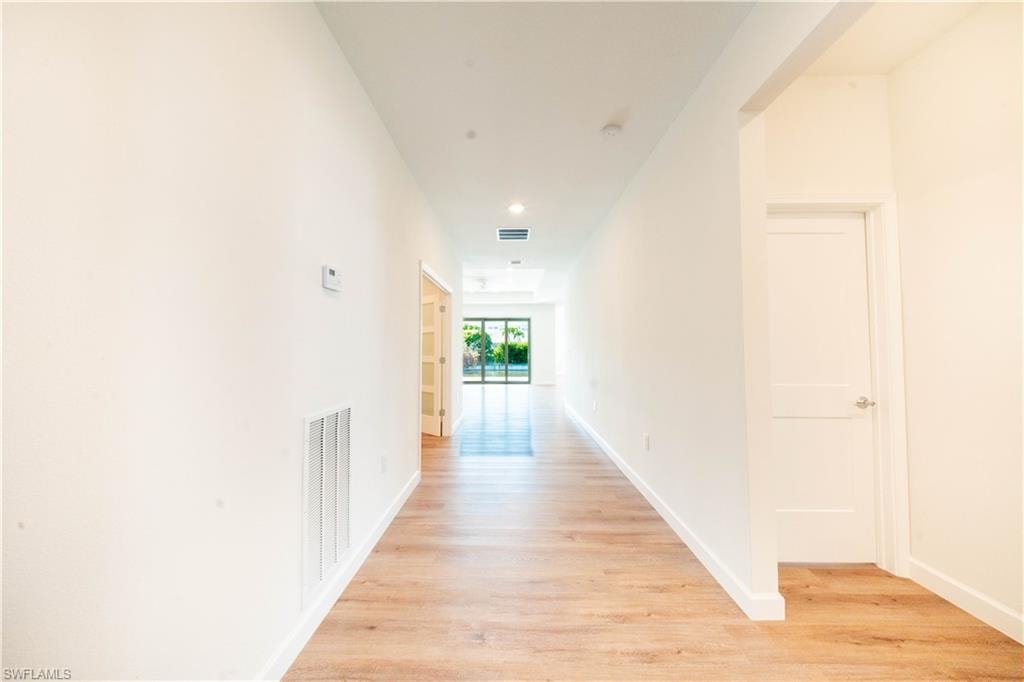 Hallway with light wood finished floors and recessed lighting