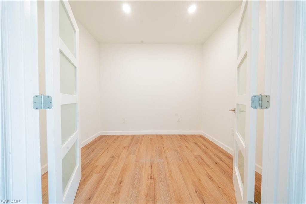 Empty room with light wood-style floors and recessed lighting