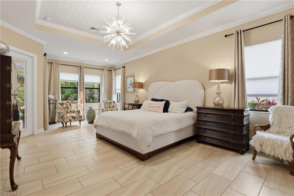Bedroom featuring a raised ceiling, access to outside, suspended lighting, and ornamental molding