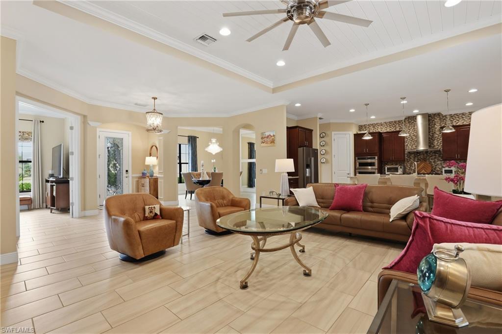 Living area featuring a ceiling fan, wood finish floors, hanging lights, a raised ceiling, and arched walkways