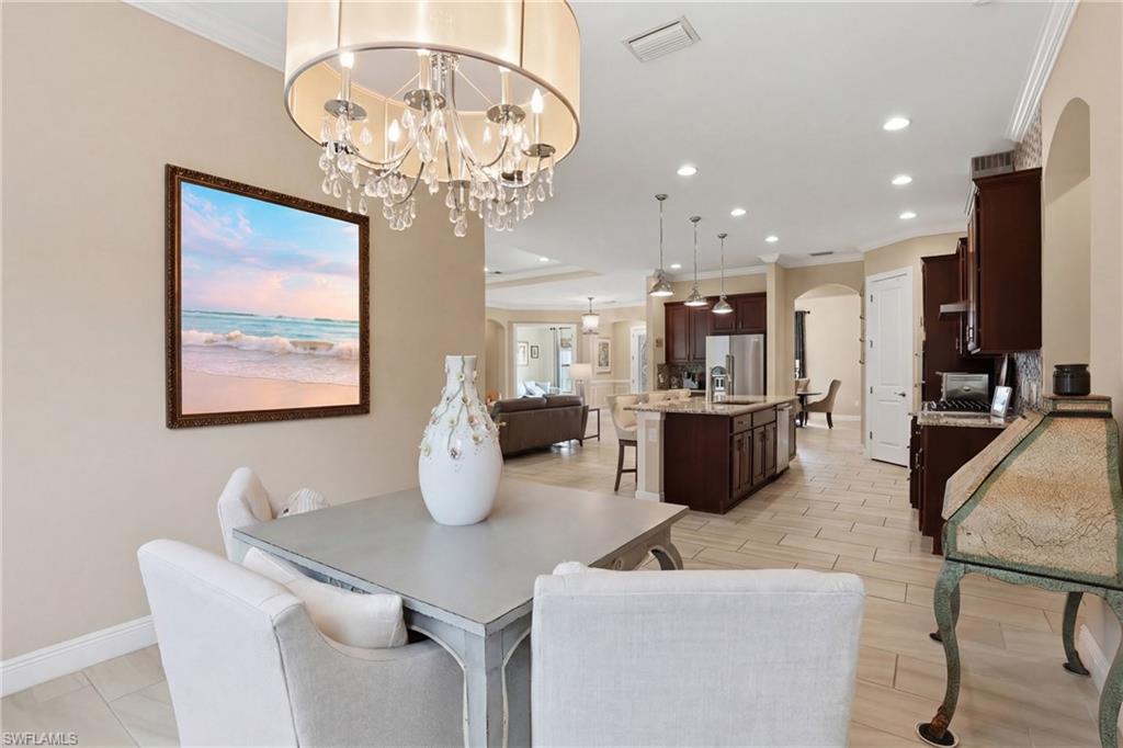 Dining space featuring crown molding, arched walkways, wood tiled floors, and a chandelier
