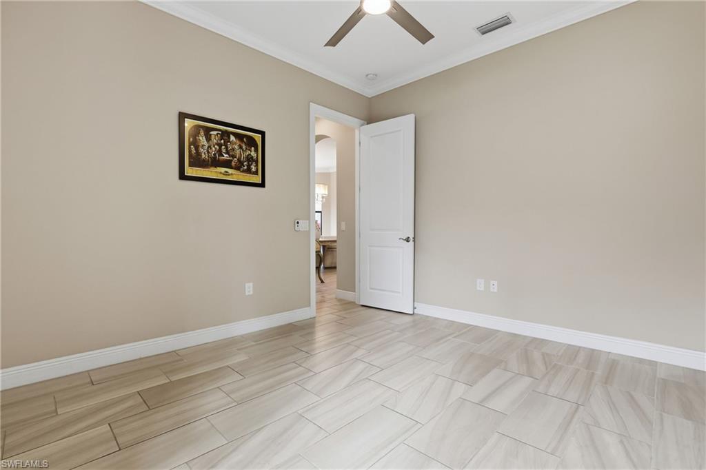 Unfurnished room with arched walkways, crown molding, and a ceiling fan
