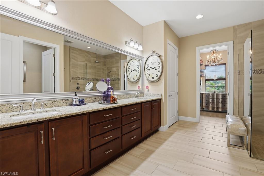 Full bath with double vanity, a shower stall, hanging lights, and wood tiled floors