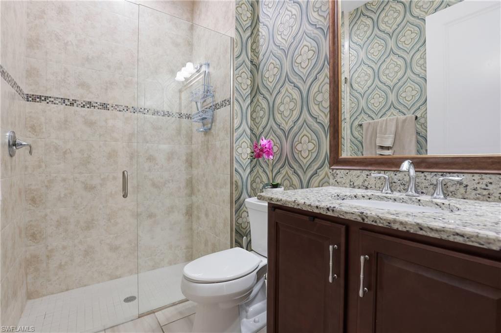 Bathroom featuring vanity, a stall shower, and wallpapered walls