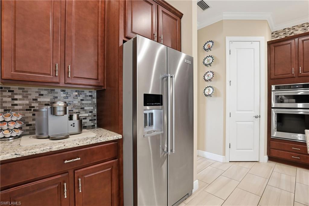 Kitchen featuring stainless steel appliances, tasteful backsplash, light stone counters, and crown molding