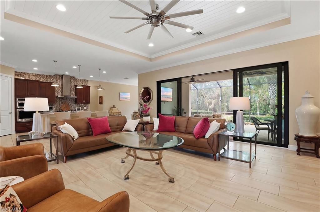Living area featuring a raised ceiling, ceiling fan, recessed lighting, and ornamental molding