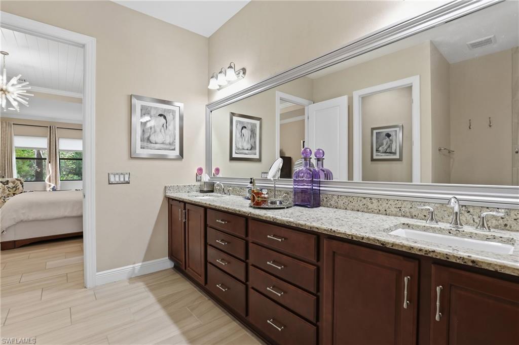 Bathroom with double vanity, ensuite bathroom, wood finish floors, and ornamental molding