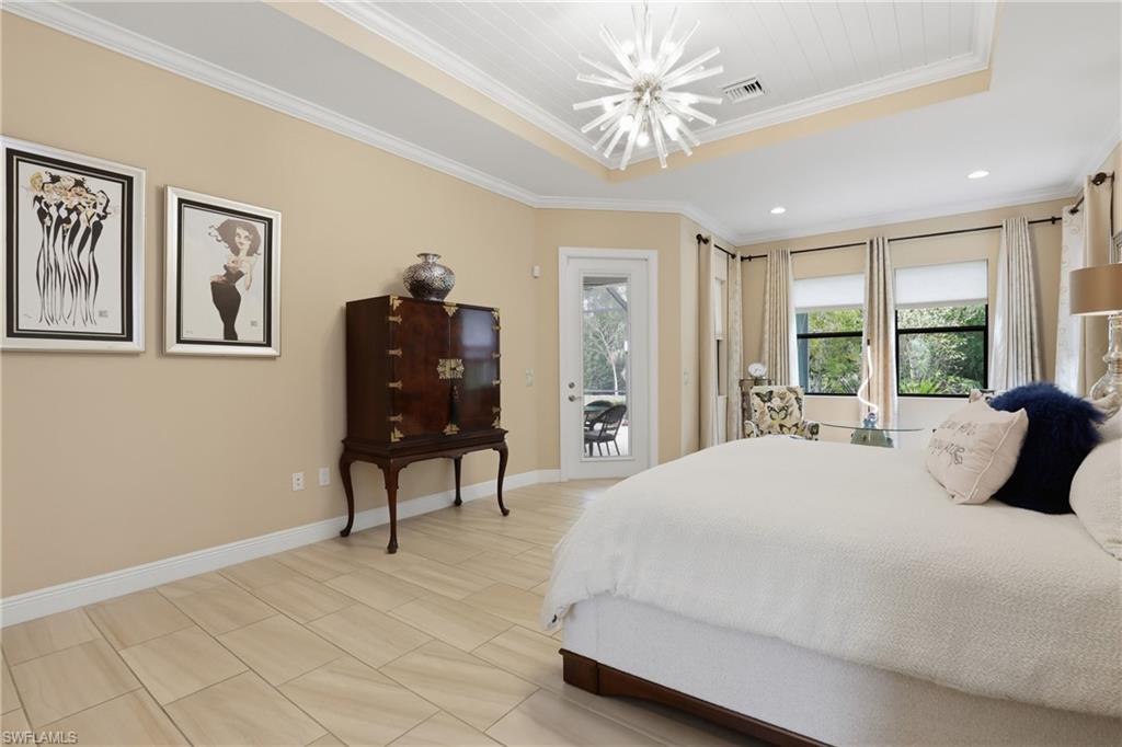Bedroom featuring a tray ceiling, ornamental molding, access to outside, and a chandelier