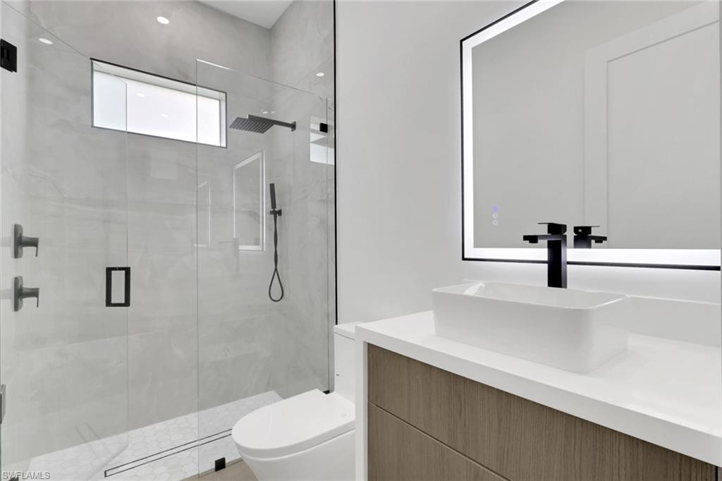 Modern bathroom featuring a walk-in shower with a rainfall showerhead, handheld shower, and light gray tiled walls