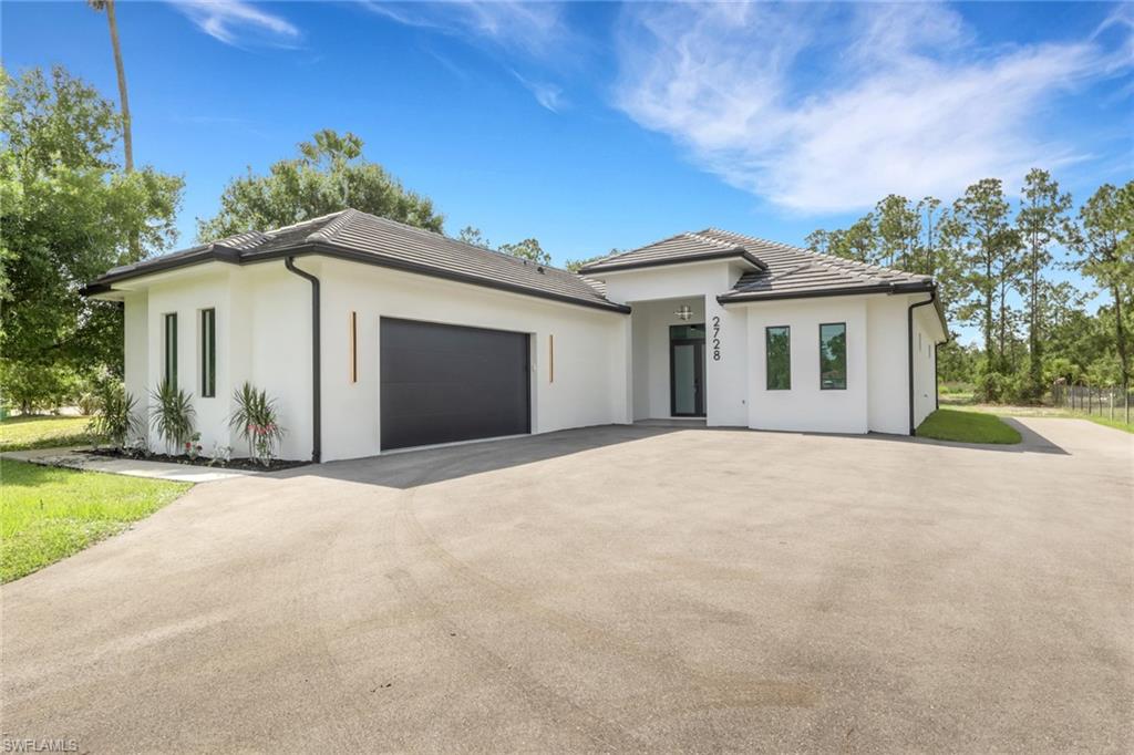 Contemporary white stucco exterior with black trim accents and a dark tile roof
