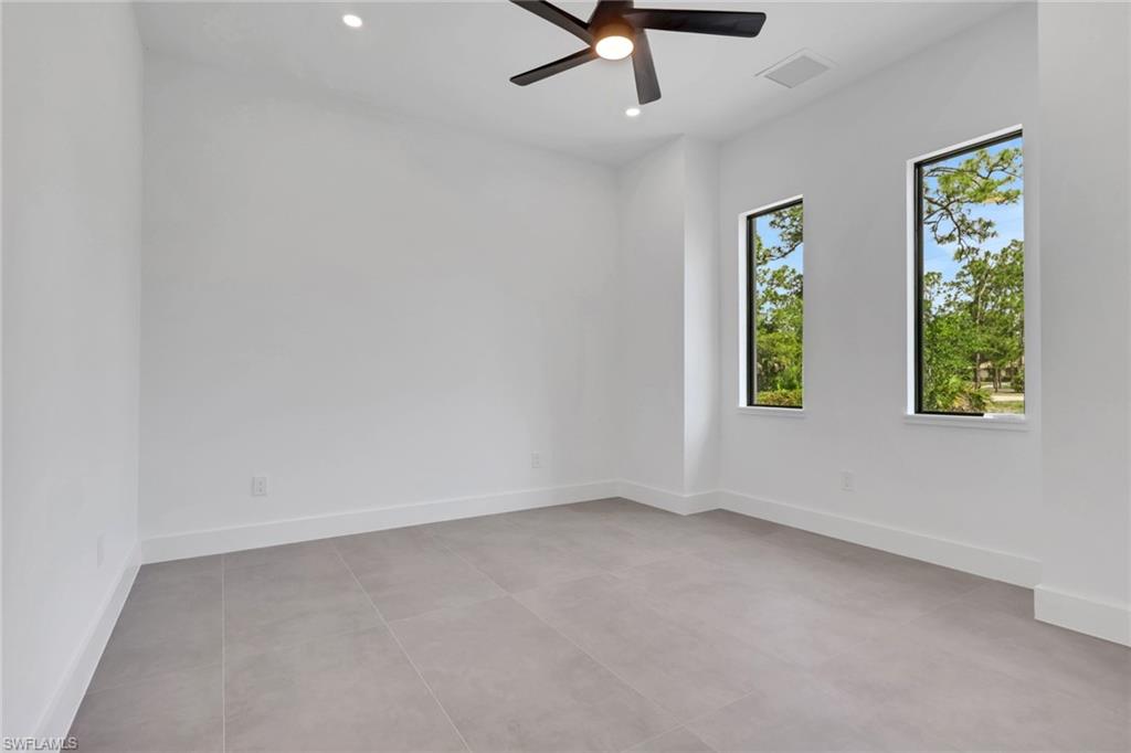 Bright interior space featuring two tall windows, a ceiling fan with integrated lighting, recessed ceiling lights, and light-toned tile flooring