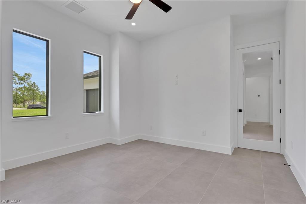 Contemporary room featuring two rectangular windows, light gray tile flooring, white baseboards, and a modern ceiling fan with lighting