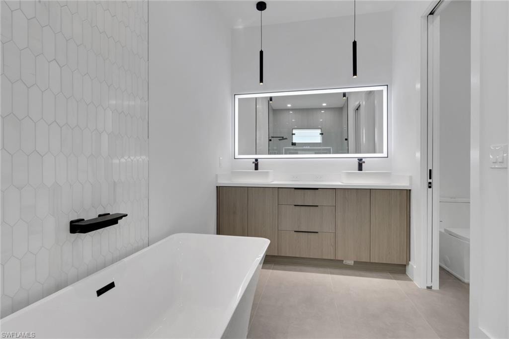 Freestanding soaking tub with a black bath shelf, complemented by a white elongated hexagonal tile wall
