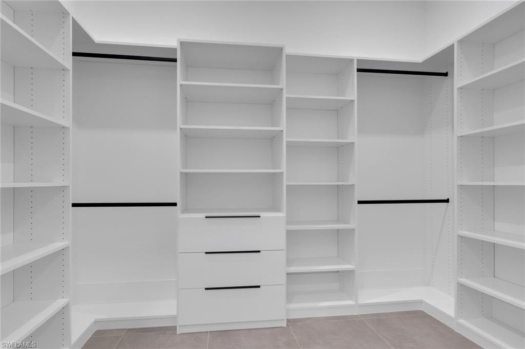 Built-in white custom closet system featuring adjustable shelving, integrated drawers with linear black pulls, and multiple hanging rods