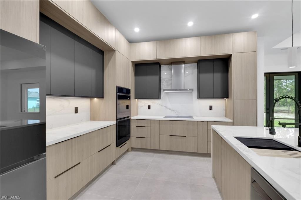 Modern kitchen featuring light wood-finish cabinetry complemented by matte black upper cabinets and integrated appliances