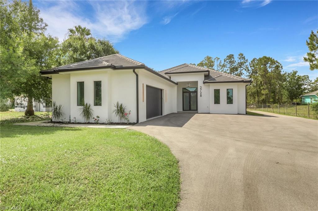 Modern architectural exterior featuring white stucco, dark trim, and a concrete tile roof